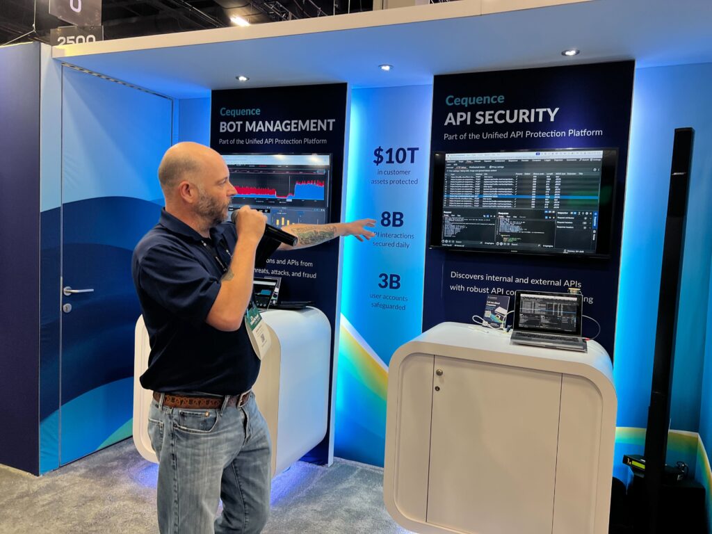 A photo of the Cequence booth staff in front of the futuristic-looking Cequence trade show booth at the Black Hat 2024 conference.