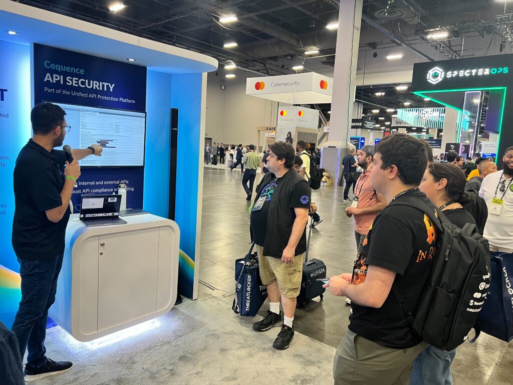 A photo of the Cequence booth staff in front of the futuristic-looking Cequence trade show booth at the Black Hat 2024 conference.