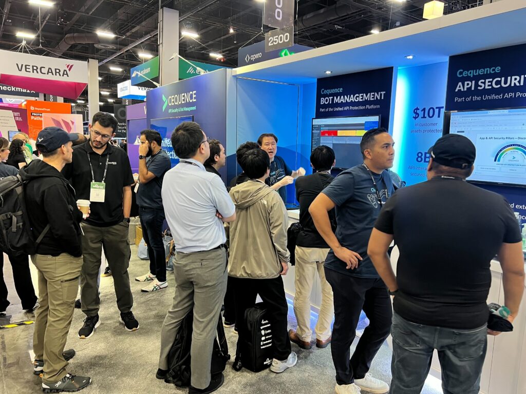 A photo of the Cequence booth staff in front of the futuristic-looking Cequence trade show booth at the Black Hat 2024 conference.